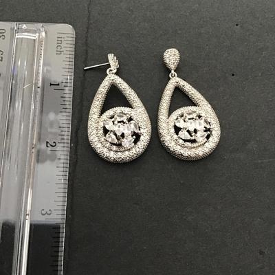 Silver toned dangle earrings with large clear, central stones in pave accent