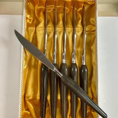 Sale Photo Thumbnail #175: Mid-Century Modern Style knives. Approx. 8.5" long, stainless steel blades and dark wood-grain handles. Satin-lined box.