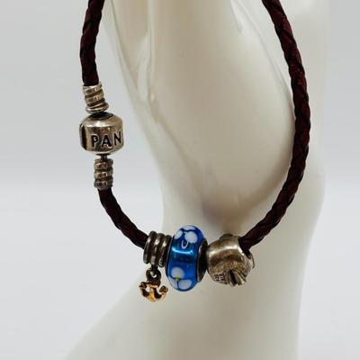 LOT 99; Pandora Leather Braided Bracelet, Blue Glass Floral Charm, Sterling Silver Smiling Budha Charm and a Dangling Anchor Charm