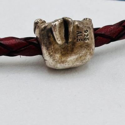 LOT 99; Pandora Leather Braided Bracelet, Blue Glass Floral Charm, Sterling Silver Smiling Budha Charm and a Dangling Anchor Charm