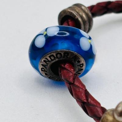 LOT 99; Pandora Leather Braided Bracelet, Blue Glass Floral Charm, Sterling Silver Smiling Budha Charm and a Dangling Anchor Charm