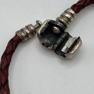 LOT 99; Pandora Leather Braided Bracelet, Blue Glass Floral Charm, Sterling Silver Smiling Budha Charm and a Dangling Anchor Charm