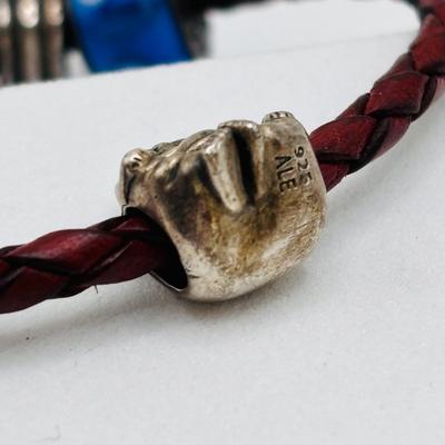 LOT 99; Pandora Leather Braided Bracelet, Blue Glass Floral Charm, Sterling Silver Smiling Budha Charm and a Dangling Anchor Charm