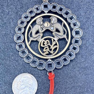 Sale Photo Thumbnail #381: Coin has an image of two monkeys facing each other.  Red cord with 2 tassels at the bottom.  Like new condition.