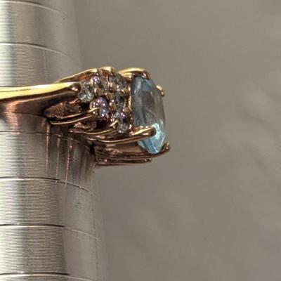 sterling silver ring with oval shaped blue topaz surrounded by small stones, likely CZ