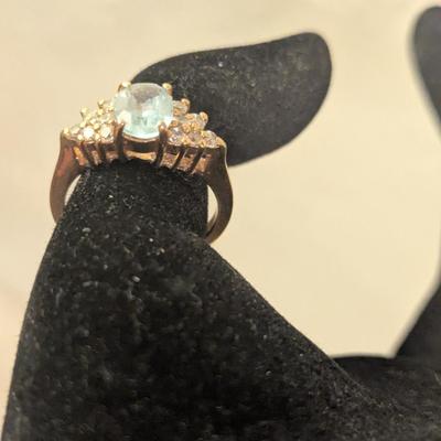 sterling silver ring with oval shaped blue topaz surrounded by small stones, likely CZ