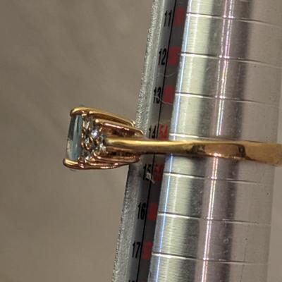 sterling silver ring with oval shaped blue topaz surrounded by small stones, likely CZ