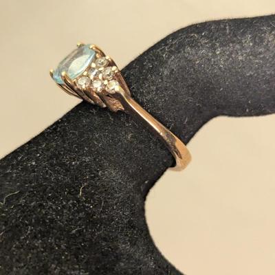 sterling silver ring with oval shaped blue topaz surrounded by small stones, likely CZ
