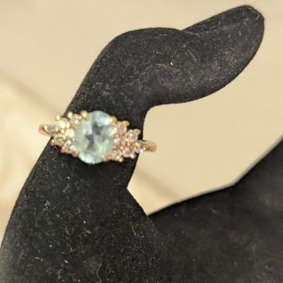 sterling silver ring with oval shaped blue topaz surrounded by small stones, likely CZ