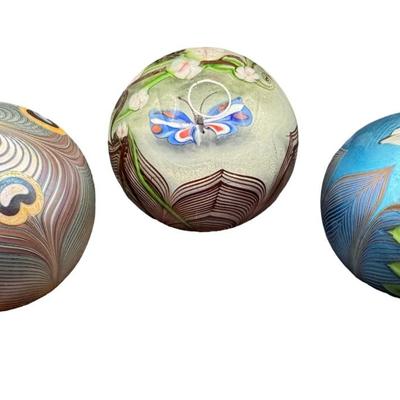 Sale Photo Thumbnail #57: Three pieces. One depicts a butterfly; one is iridescent with flower and feathers; and one is iridescent with pulled feathers. Measurement of largest: 3.5” Diameter. Pre-auction estimate: $300-$500. [MA]