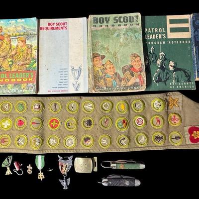 Sale Photo Thumbnail #129: Includes two Boy Scout pocket knives, a belt buckle, three medals, an Eagle Scout award in sterling silver, a merit badge sash, and six books. Total of 14 pieces. [KD]