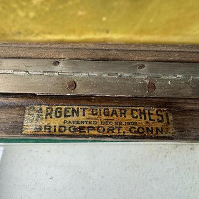 Sale Photo Thumbnail #162: Made in U.S.A. This has dovetailed wood construction, a glass lining, and a brass humidor unit on the underside of the lid. There is some age related wear. Not tested. Measurement: 11.5”L x 8”W x 6.5”H. [KD]