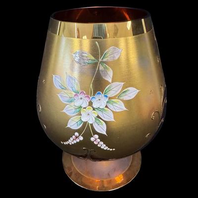 Sale Photo Thumbnail #163: This cranberry glass vase has raised flowers and ornate gold decoration. There is still a paper label affixed. No obvious chips or cracks. Measurement: 8”H x 6” Diameter (at widest point). Pre-auction estimate: $50-$100. [RE]