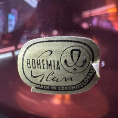 Sale Photo Thumbnail #165: This cranberry glass vase has raised flowers and ornate gold decoration. There is still a paper label affixed. No obvious chips or cracks. Measurement: 8”H x 6” Diameter (at widest point). Pre-auction estimate: $50-$100. [RE]