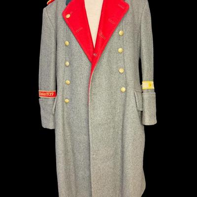 Sale Photo Thumbnail #172: This would have been worn by a General Officer. It is possibly a reproduction or prop. Made from wool, in a field grey color. The red piping on the cuffs aligns with an M36 model greatcoat. Possibly size XL. This has been in a smoky environment, and needs