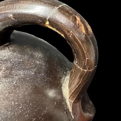 Sale Photo Thumbnail #187: This jug has a deep brown glaze. There is a chip on the base, and the handle has been repaired. There is general age related wear, including some surface scratches. Measurement; 10”H x 7”W. [SR]
