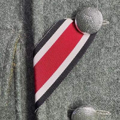 Sale Photo Thumbnail #190: This is greenish-grey wool, which was standard issue. It features four pleated patch pockets with scalloped flaps. It has a ribbon for the Iron Cross Second Class. It is possibly a reproduction or prop. The size is approximately medium to large. This has 