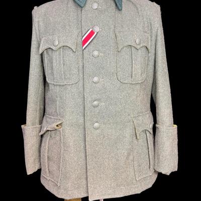 Sale Photo Thumbnail #189: This is greenish-grey wool, which was standard issue. It features four pleated patch pockets with scalloped flaps. It has a ribbon for the Iron Cross Second Class. It is possibly a reproduction or prop. The size is approximately medium to large. This has 