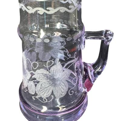 Sale Photo Thumbnail #288: Made in Czechoslovakia. Includes two purple etched beer mugs, and one amber delicate glass vase. Total of three pieces. One of the mugs has a chip on the rim (pictured). Measurement of tallest: 7”H. Pre-auction estimate: $75-$125. [RE]