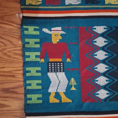 handwoven Guatemalan textile or tapestry, depicting human figures and animal motifs. 