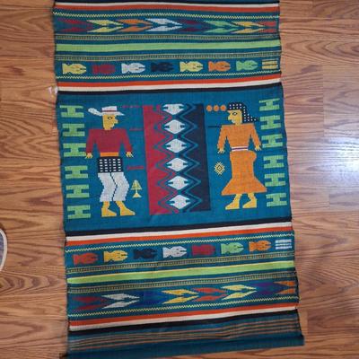 handwoven Guatemalan textile or tapestry, depicting human figures and animal motifs. 