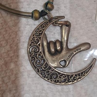 silver tone charm necklace with a pendant and hand making the I love you sign in American Sign Language.