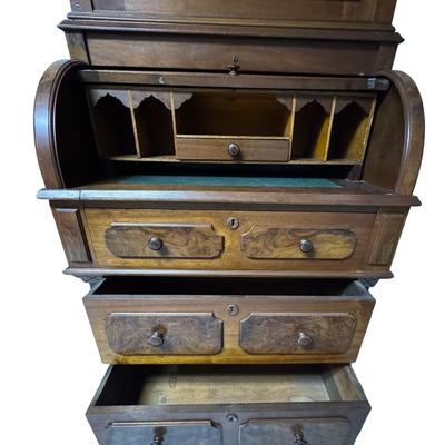 Sale Photo Thumbnail #331: Two piece design featuring a bookcase on top. The lower portion features the cylinder roll. It is most likely made from walnut, with a possible veneer. There is age related wear, including one missing section of moulding on the top right side. Measurement