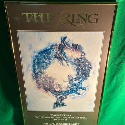 Sale Photo Thumbnail #96: Framed 'The Ring' Seattle Opera poster from the Wagner Festival, dated 1989. Features a vibrant artistic depiction of Wagnerian themes, underlined with gold text detailing the event specifics, including dates of July 23 to August 12, 1989. Set in a gold-t