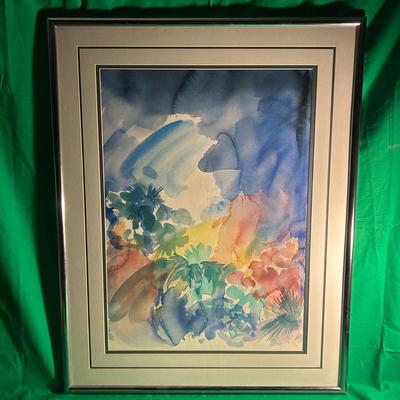 Sale Photo Thumbnail #112: A framed abstract watercolor painting featuring a bold, colorful composition of blues, greens, pinks, and yellows. The artwork is bordered by a double mat in neutral tones and encased in a silver-toned metal frame with a glass cover. The frame shows light