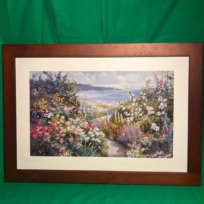 Sale Photo Thumbnail #118: Framed landscape painting featuring a vibrant garden scene with colorful flowers in the foreground and an ocean view in the background. The artwork is set in a wooden frame with a white mat board. The frame displays light wear consistent with handling. Me