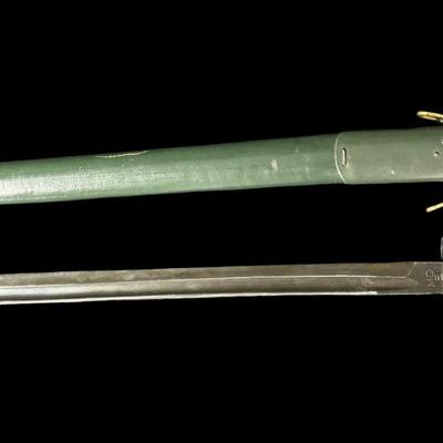 Sale Photo Thumbnail #538: This is an exact reproduction of the classic WW1 Enfield M-1917 bayonet. It has hardwood grips, and comes with a steel-mounted leather scabbard complete with correct hooks. This bayonet was also the standard issue for military shotguns, AKA “Trench Guns