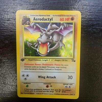 Sale Photo Thumbnail #11: First Edition Aerodactyl Pokemon card from the 1999 Fossil set. Features 60 HP and the attacks Prehistoric Power and Wing Attack. Includes the First Edition stamp on the cardâ€™s lower-left area. Card has standard layout with 1999-2000 Wizard of the 