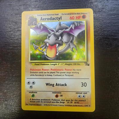 Sale Photo Thumbnail #17: Aerodactyl card from the Base Set Fossil series, showcasing the iconic Aerodactyl illustration. Card is in Light Play condition, exhibiting minor signs of wear. It features 60 HP and notable moves including Wing Attack (30 damage). A collectible for fans 