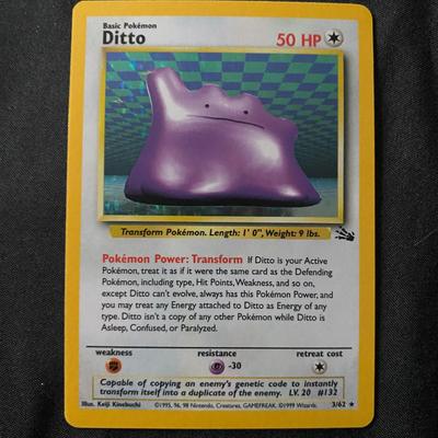 Sale Photo Thumbnail #45: 1999 Pokemon TCG Holo Ditto card from the Fossil set, featuring the Basic Ditto with 50 HP and the 'Transform' ability. Card has light play wear, as seen on both the front and back. A clean holofoil with some typical minor surface imperfections. An iconic