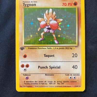Sale Photo Thumbnail #83: Pokemon card featuring Tygnon, a holographic (holo) first edition card. Released as part of the early base set series. Text in French. Condition is marked as light play, indicating minor wear from handling. The card displays holographic elements with dist