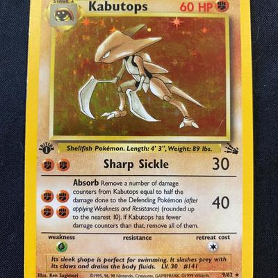 Sale Photo Thumbnail #93: Pokemon TCG Kabutops 1st Edition Holo card from the Fossil Set. Stamped with 'Edition 1' indicating first run print. Condition is light play with minor surface and edge wear but no major damage. Collector number: 9/62. Manufactured by Wizards of the Coast