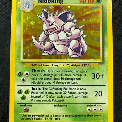 Sale Photo Thumbnail #119: Pokemon Base Set Nidoking, card number 11/102, Holofoil, 1999 edition. Condition is light play with visible wear consistent with light usage. Features 90 HP, 'Thrash' and 'Toxic' attacks. Printed by Wizards of the Coast. Original English-language release.