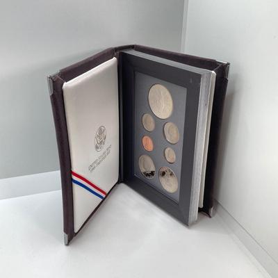 LOT 105: United States Mint 1989 Prestige Set with 1989 Congressional Silver Dollar and Half Dollar in Presentation Book with Certificate...