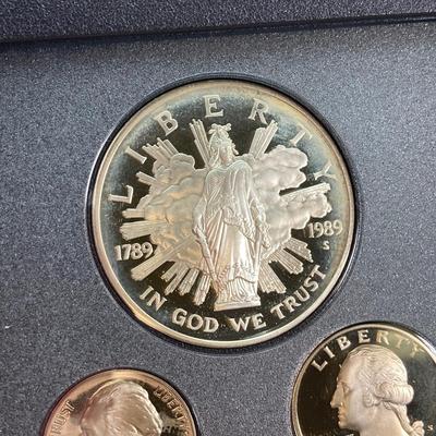 LOT 105: United States Mint 1989 Prestige Set with 1989 Congressional Silver Dollar and Half Dollar in Presentation Book with Certificate...