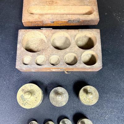 Sale Photo Thumbnail #666: Antique set of brass scale weights in a wooden box. 7 weights are included, the smallest one is missing.  Box hinge is broken.
