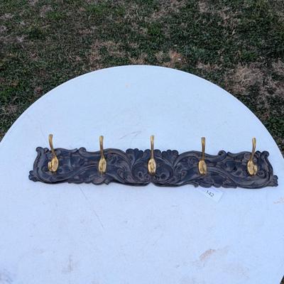  wall-mounted coat and hat rack with six brass-toned hooks.