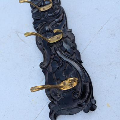  wall-mounted coat and hat rack with six brass-toned hooks.