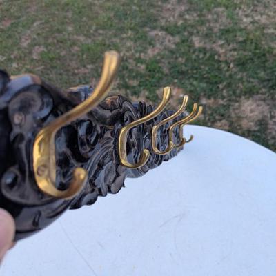  wall-mounted coat and hat rack with six brass-toned hooks.