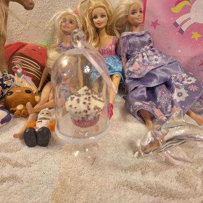 various dolls and toys, barbie, horse and other items all in a unicorn bagq