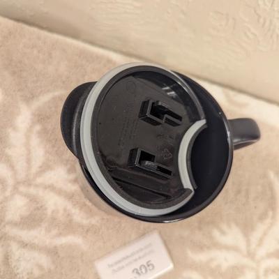 black ceramic mug with a cork base and lid, featuring the Comanche Nation "Lords of the Plains" logo