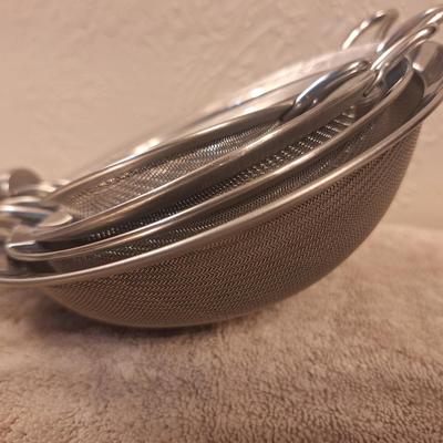 Set of stainless steel fin mesh strainers.