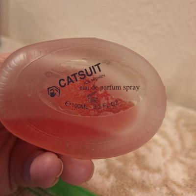 Left: A bottle of Creation Lamis Catsuit Eau de Parfum for Women.  Right: A bottle of Sheer Attraction by Intimate Silkening Body Mist in...