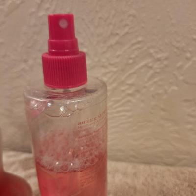 Left: A bottle of Creation Lamis Catsuit Eau de Parfum for Women.  Right: A bottle of Sheer Attraction by Intimate Silkening Body Mist in...