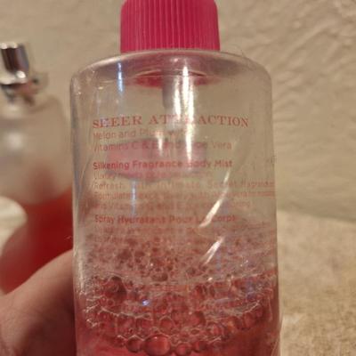 Left: A bottle of Creation Lamis Catsuit Eau de Parfum for Women.  Right: A bottle of Sheer Attraction by Intimate Silkening Body Mist in...