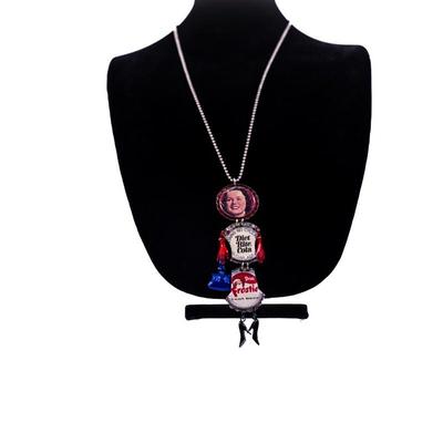 Sale Photo Thumbnail #419: This is a handmade novelty necklace made from vintage Pabt Blue Ribbon and Frostie Root Beer bottle caps. Its features a figural design resembling a person, with the bottle caps forming the body and painted metal pieces for the limbs.